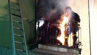 Un materasso prende fuoco mentre un pompiere tenta di portarlo via dalla casa